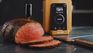 Wireless meat thermometer measuring steak temperature on grill