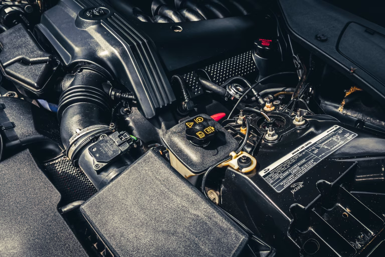 Mechanic inspecting engine compartment for signs of a failing car alternator