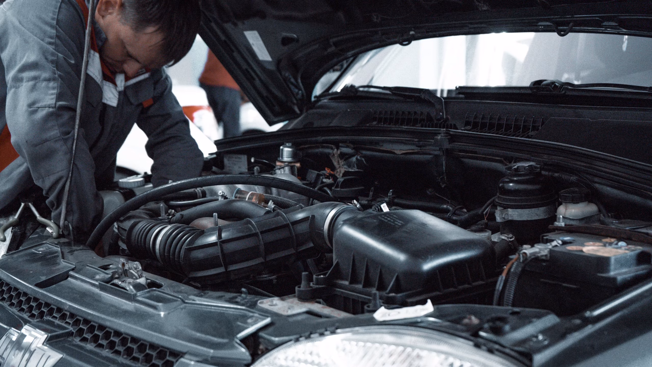 Mechanic using brush while learning how to clean car engine bay safely